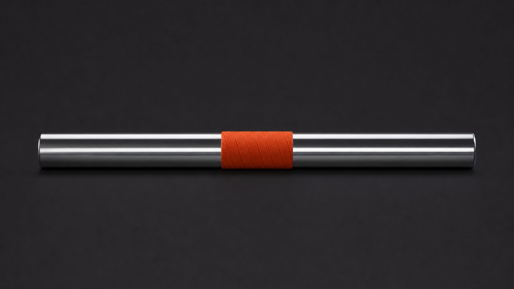 A polished steel relay baton with an orange grip band on a graphite background.