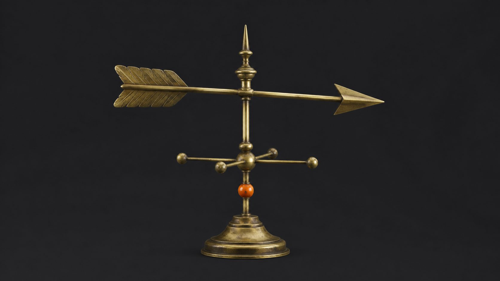 A brass weathervane with an orange directional arrow on a graphite background.