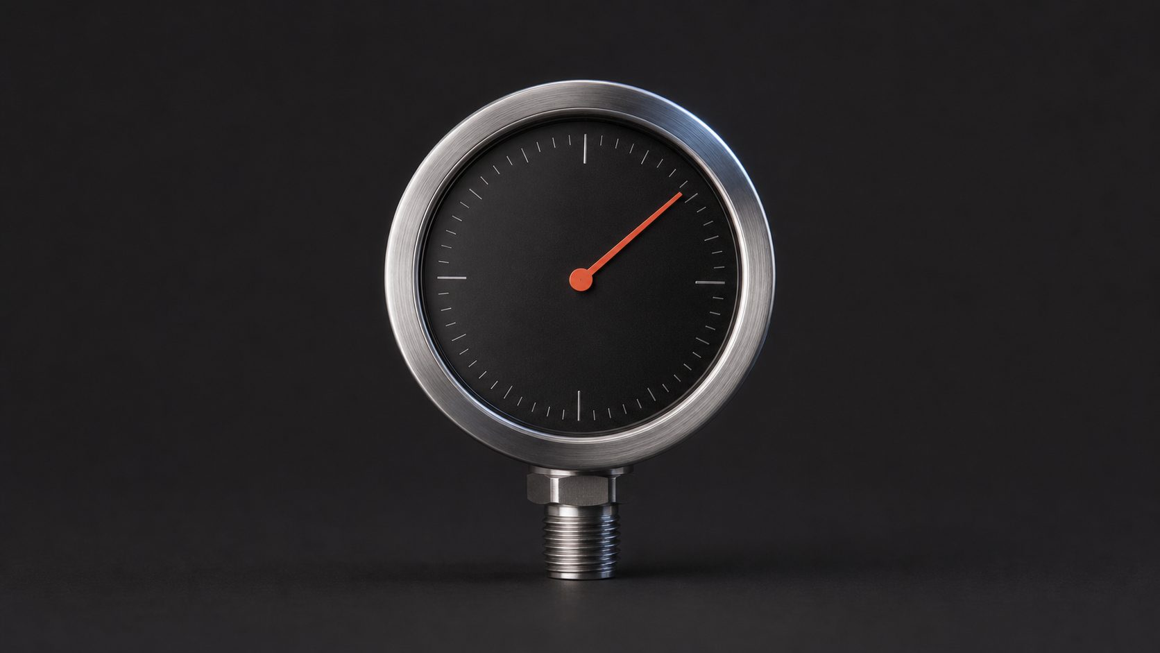 A precision pressure gauge with an orange needle on a graphite background.