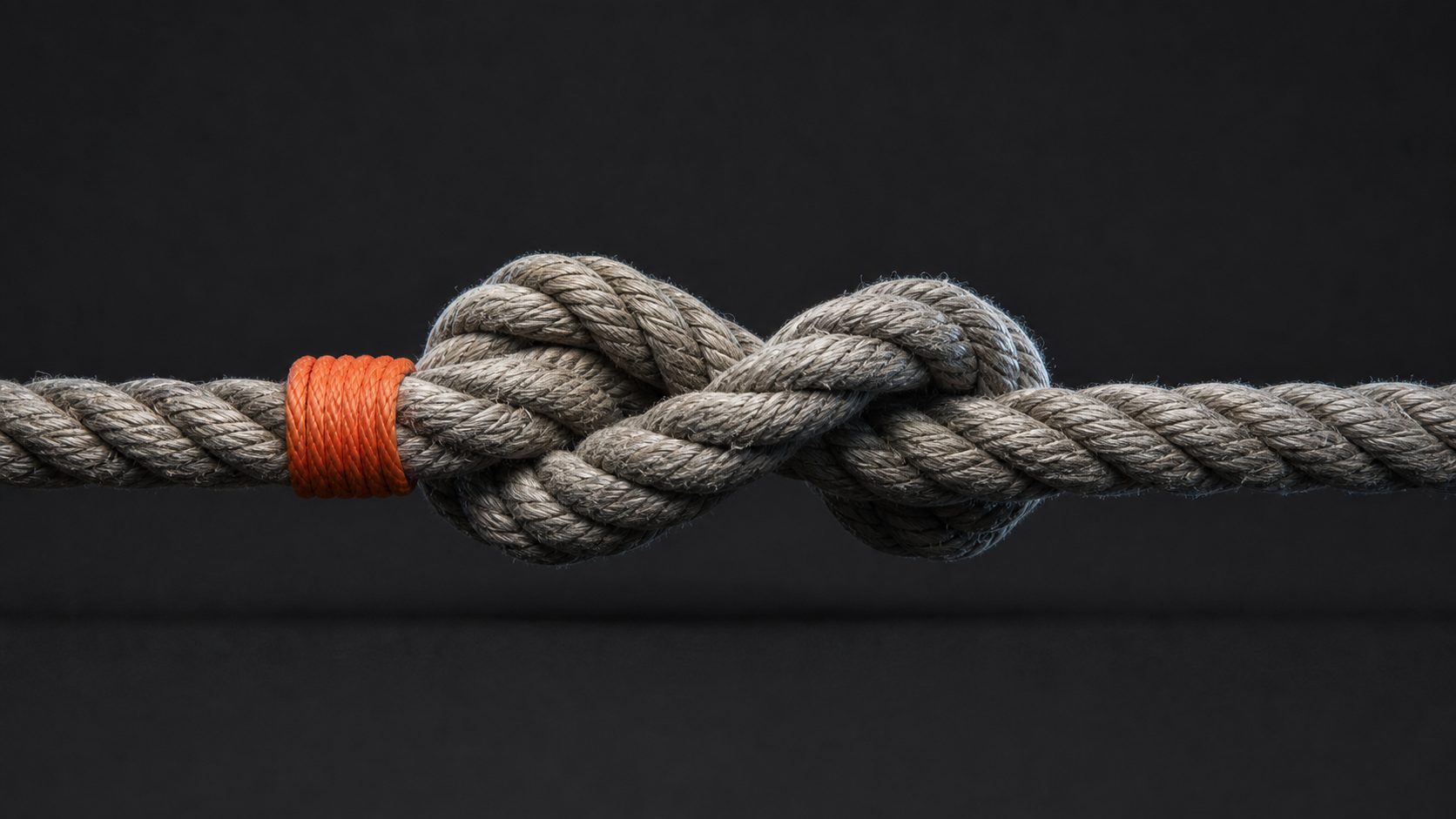 A figure-eight knot pulled taut in marine rope with one orange strand.