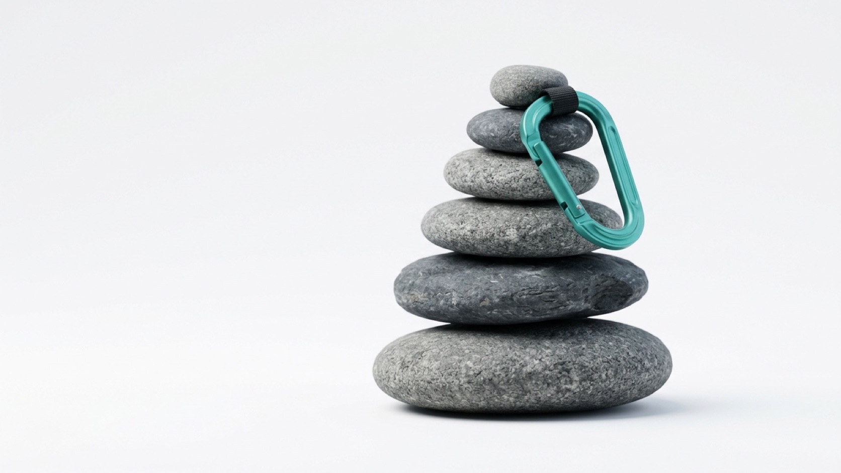 A balanced stone cairn with a teal climbing carabiner clipped to the top stone